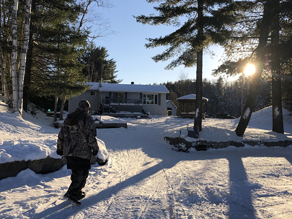 Man walking towards a cottage in the snow.